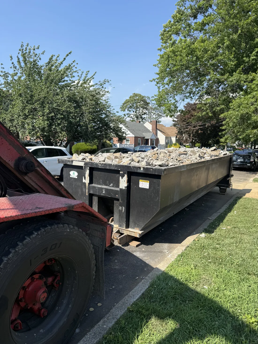 Pyrate Dumpsters 20-yard concrete dumpster loaded with concrete and masonry debris, ready for pickup in Nassau County