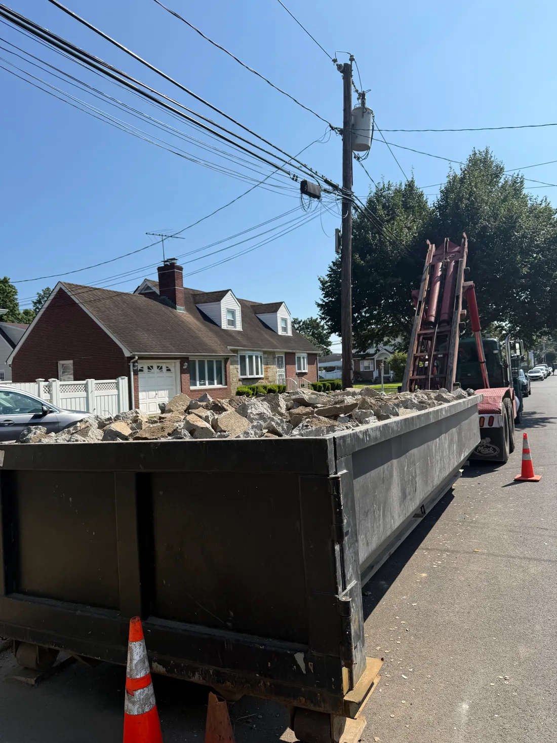 Pyrate Dumpsters 20-yard roll-off dumpster filled with broken concrete on a residential street in Nassau County, NY