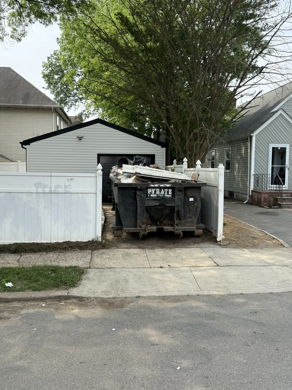 Pyrate Dumpsters 20-yard roll-off dumpster loaded with debris on a residential driveway in Westbury, NY