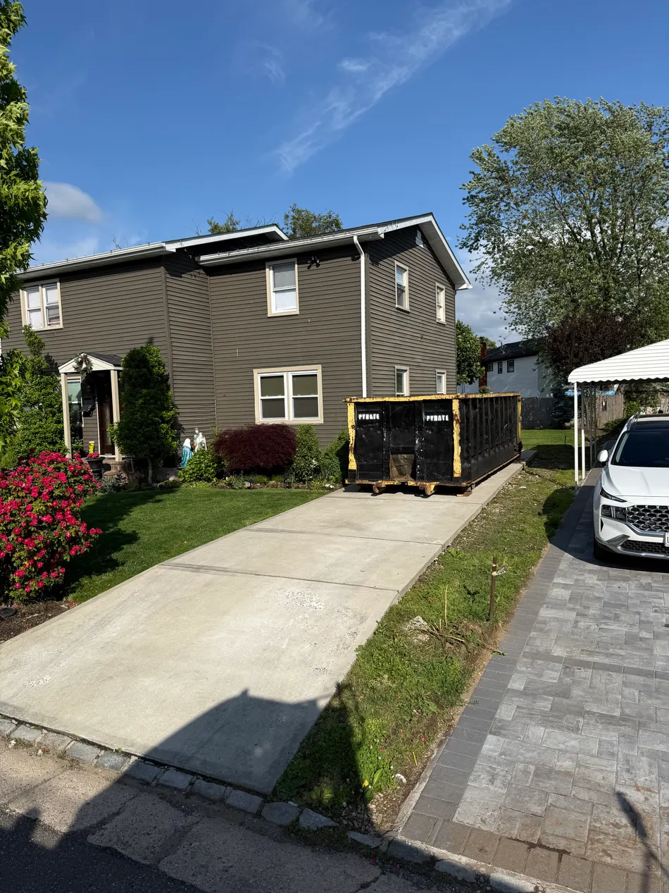 Pyrate Dumpsters roll-off dumpster on a residential paver driveway in Williston Park, NY